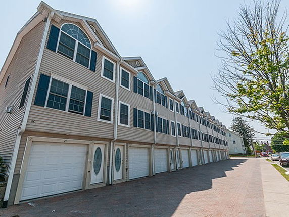 Front view of a row of multi-story townhouses with garages.