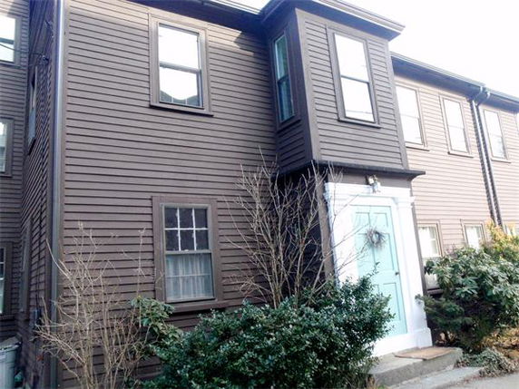 Front view of a two-story house with brown siding and a light blue door.