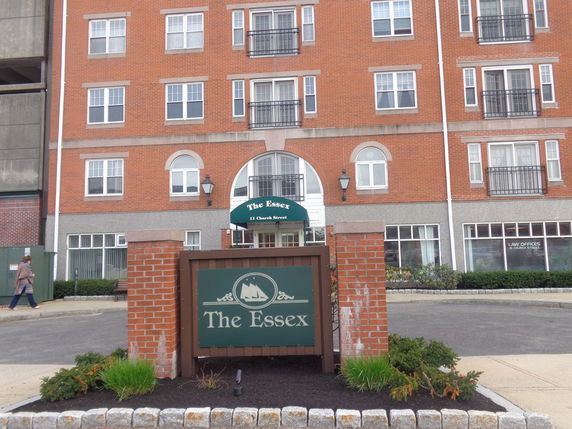 Front view of a multi-story brick building with multiple windows and an entrance sign labeled 'The Essex'.