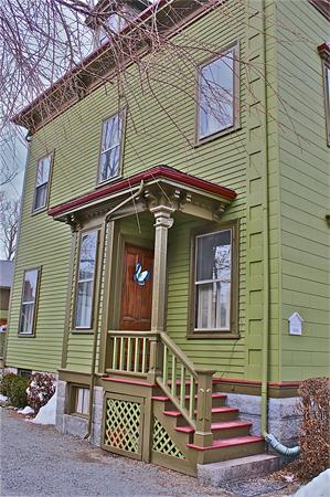Front view of a two-story house with green siding and a wooden door.