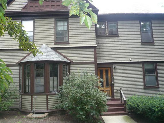 Front view of a two-story house with brown siding and bay window.