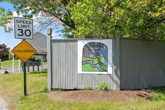 Front view of a sign for Winding Brook Estates near a speed limit warning.