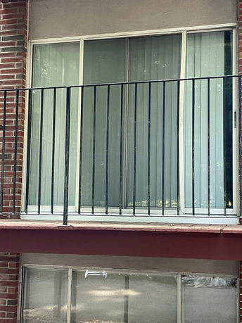 Rear view of a balcony with metal railing and sliding glass doors.