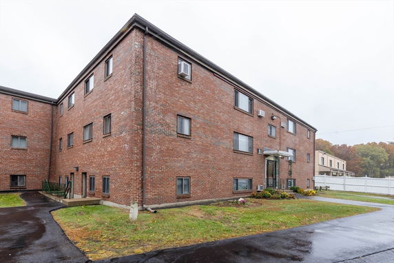 Front view of a brick, multi-storey apartment building with several windows and a small entrance canopy.