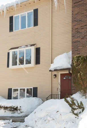 Front view of a multi-story house with snow on the ground.