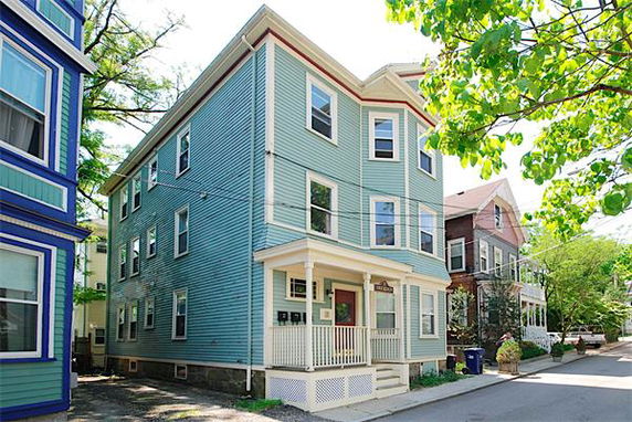 Front view of a three-story house with blue siding and a small porch.