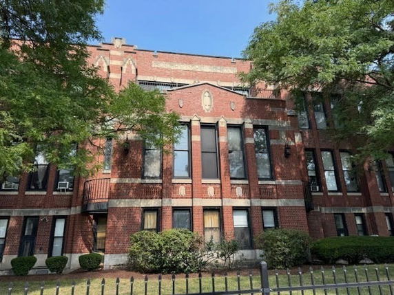 Front view of a multi-story brick building with large windows.