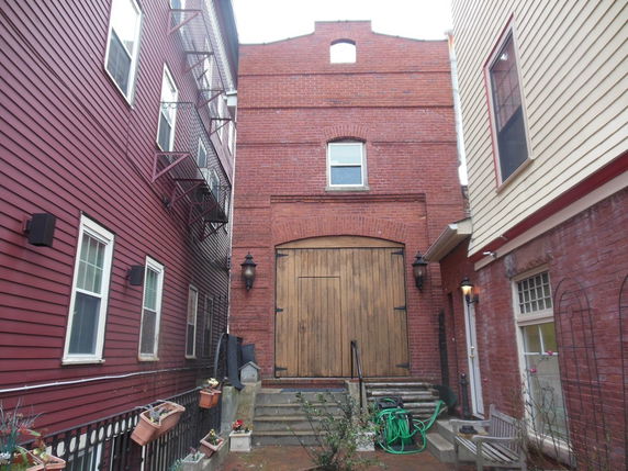 Front view of a brick building with a large wooden door.