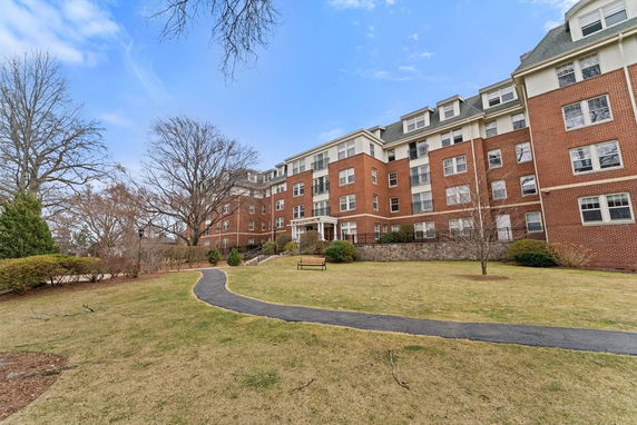 Front view of a multi-story brick building with a sloped roof.