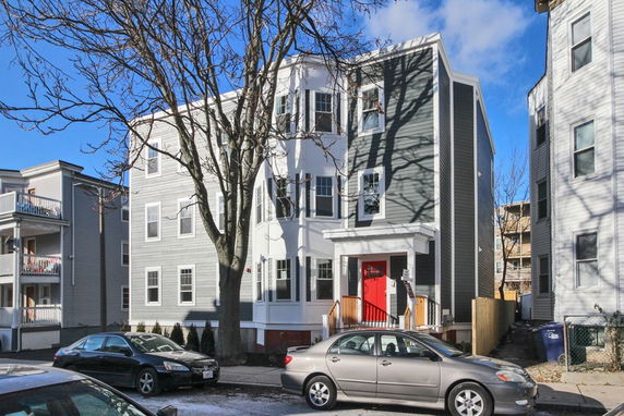 Front view of a multi-story residential building with a red front door.