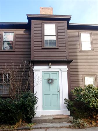 Front view of a two-story house with a light blue door and brown siding.