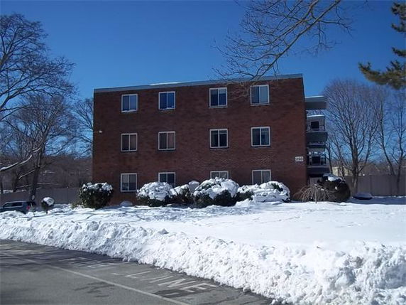 Front view of a three-story brick apartment building with multiple windows and a flat roof.