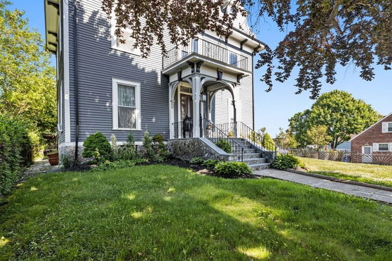 Front view of a two-story house with a porch and stairs leading to the entrance.