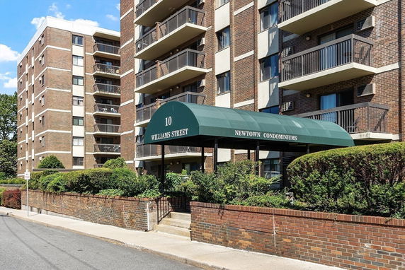 Front view of a multi-story condominium building with a green canopy entrance.