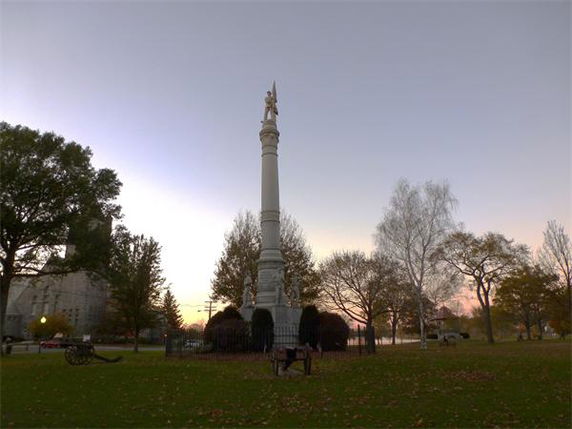 A tall monument surrounded by trees in a park setting.