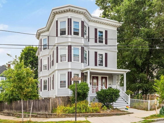 Front view of a three-story house with white siding and maroon shutters.