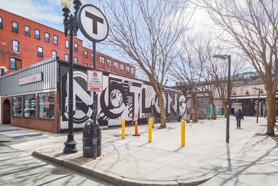 Front view of a commercial building with a mural and street signage.