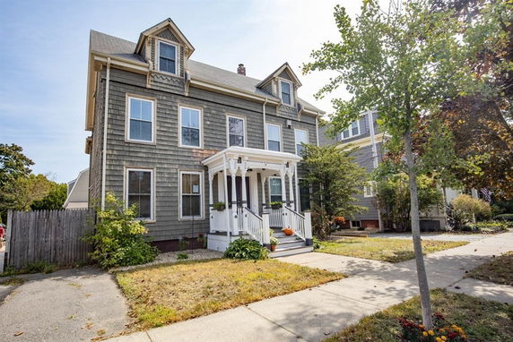 Front view of a two-story house with triangular roof dormers and a small porch.
