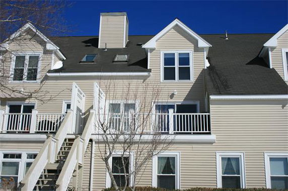 Front view of a multi-story house with balconies and stairs.