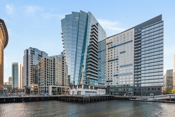 Front view of a modern high-rise building complex with glass facades by the water.