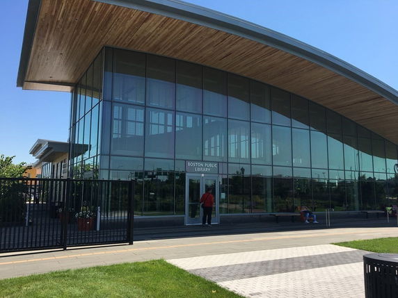 Front view of a modern public library building with a large glass facade and curved roof.