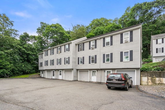Front view of a multi-story residential building with garage doors at the ground level.