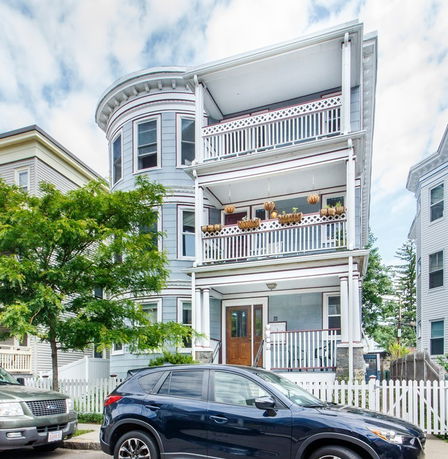 Front view of a multi-story house with balconies and a rounded corner.