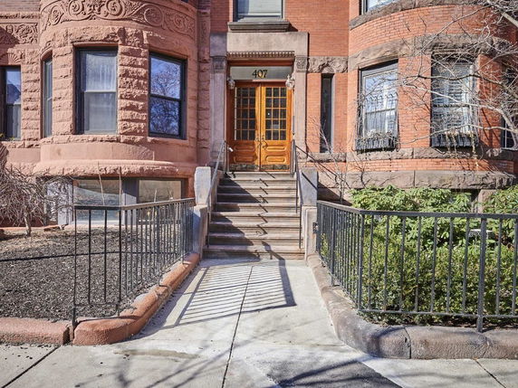 Front view of a brick townhouse with a stepped entrance and ornate architectural details.