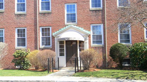Front view of a brick apartment building with multiple windows and an entryway.