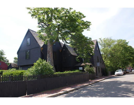 Front view of a dark, multi-story house with a steeply pitched roof and large trees surrounding it.
