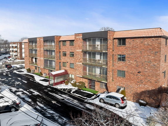 Front view of a multi-story brick apartment building with balconies.
