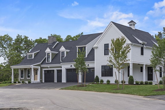 Front view of a two-story house with black garage doors and white siding.
