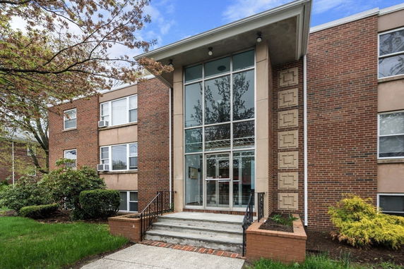 Front view of a brick apartment building with large glass entrance.