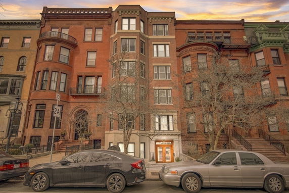 Front view of a multi-story brick building with large windows and ornate detailing.