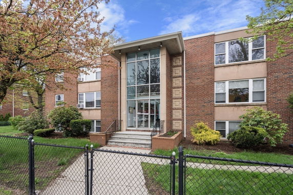 Front view of a brick apartment building with large glass windows in the entrance.