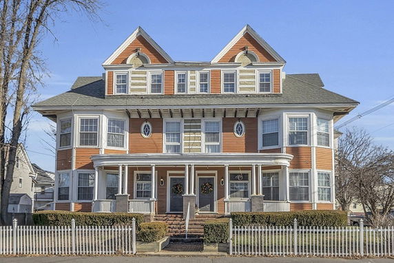 Front view of a large multi-story house with a distinctive architectural design and a symmetrical facade.