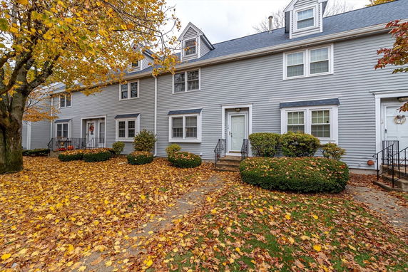 Front view of a multi-story house with multiple entrances and autumn leaves on the ground.