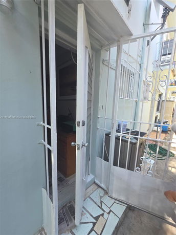 Partial view of a building entrance with an open metal gate and door.