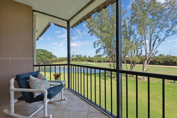 Balcony view of a golf course with trees and a pond in the background.