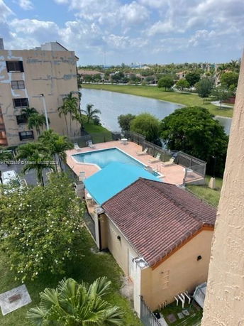 View of a building with a pool and surrounding greenery.
