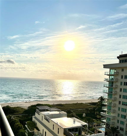 Panoramic view from a building showing the ocean and adjacent beach with a nearby building.
