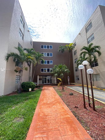 Front view of a multi-story residential building with a walkway leading to the entrance.