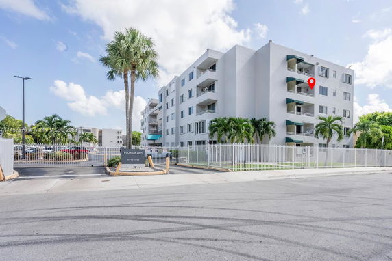 Front view of a multi-story apartment building with balconies and a gated entrance.