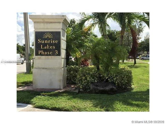Entrance sign for Sunrise Lakes Phase 3 surrounded by greenery.
