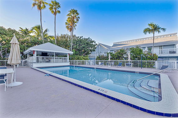 Outdoor swimming pool area with a gazebo and surrounding trees.