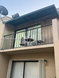 Front view of a building with a balcony and sliding glass door on the upper level.