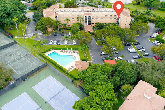 Aerial view of a residential complex with parking, swimming pool, and tennis courts.