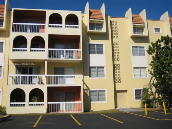 Front view of a multi-story apartment building with balconies and arched openings.