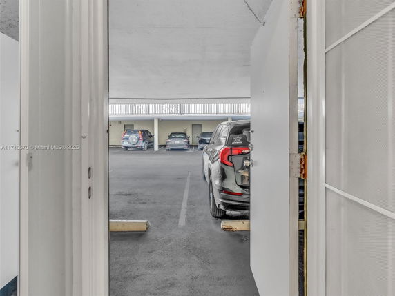 Covered parking area with several vehicles parked.