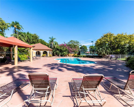 Outdoor swimming pool area with sun loungers and a small pool house.